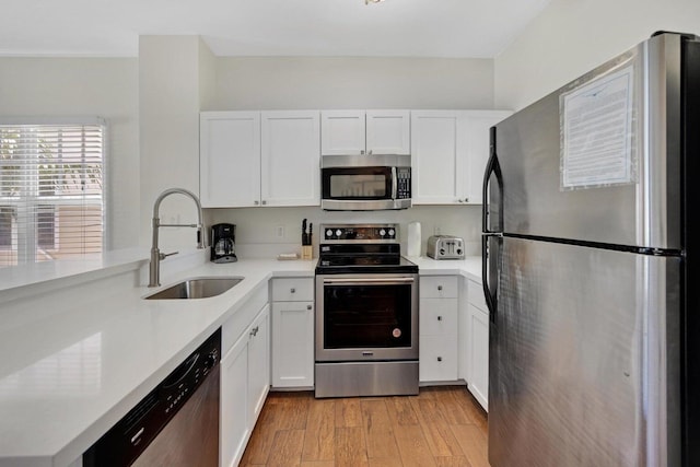 kitchen with white cabinetry, appliances with stainless steel finishes, light countertops, and a sink
