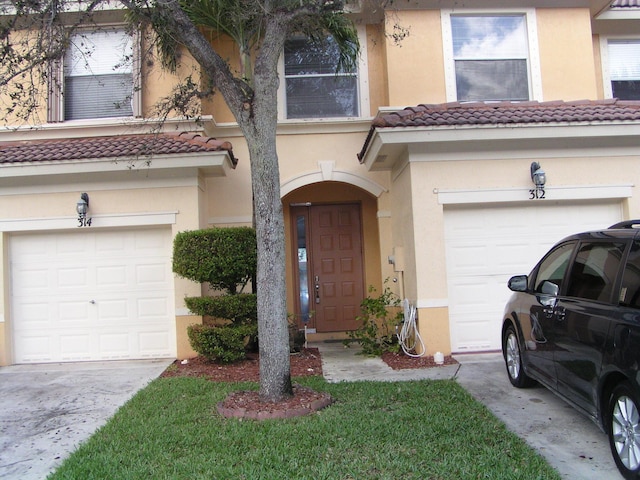 312 River Bluff Ln, Royal Palm Beach, FL 33411 - townhome / multi-family property featuring a tiled roof, a garage, stucco siding, and driveway