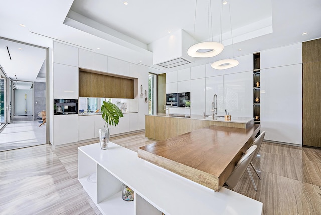 interior space featuring modern cabinets, white cabinetry, light countertops, a sink, and decorative light fixtures