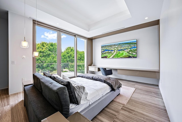 bedroom featuring a tray ceiling, wood finished floors, and recessed lighting