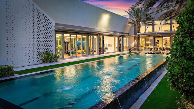 back of property with a patio area and an infinity pool