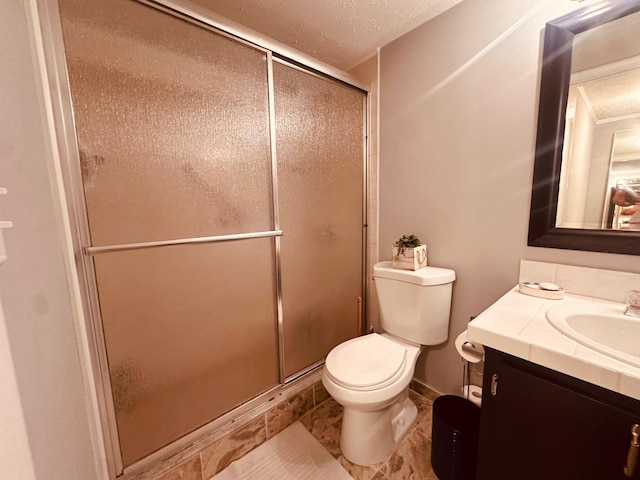 bathroom featuring toilet, a stall shower, a textured ceiling, and vanity