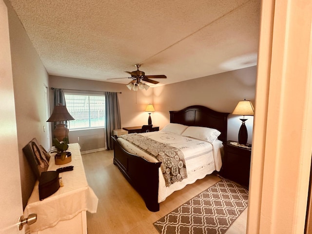 bedroom with light wood-type flooring, a textured ceiling, and a ceiling fan