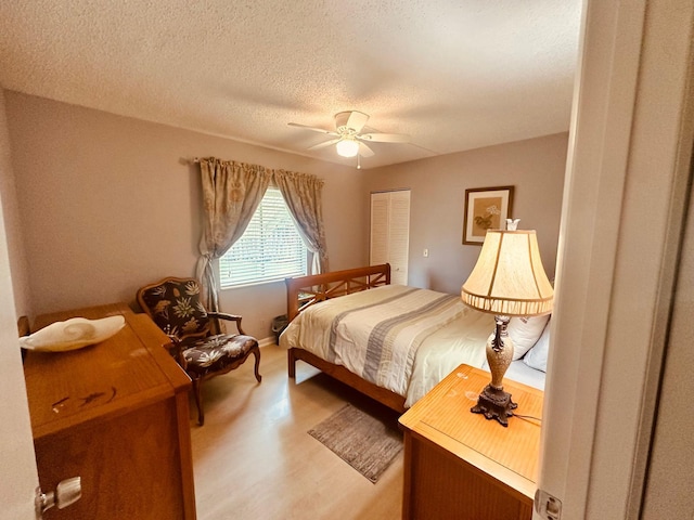 bedroom with ceiling fan, a textured ceiling, a closet, and light wood-style flooring