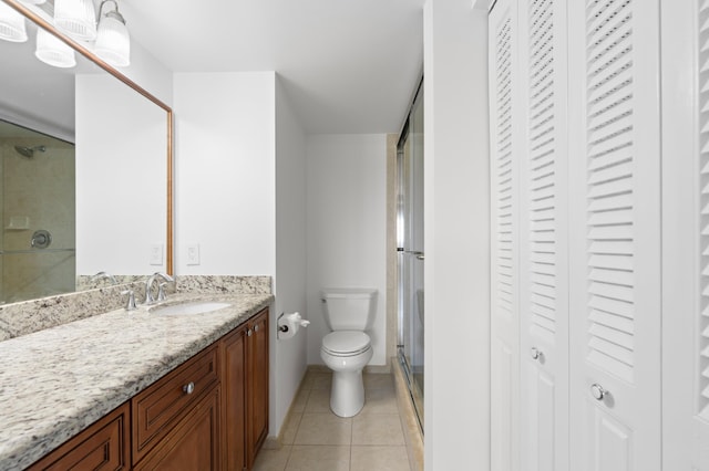 full bath with tile patterned flooring, toilet, vanity, a closet, and a stall shower