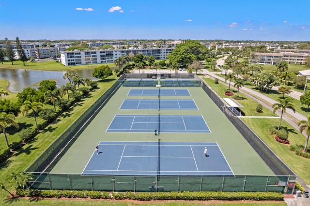 view of tennis court with fence and a water view