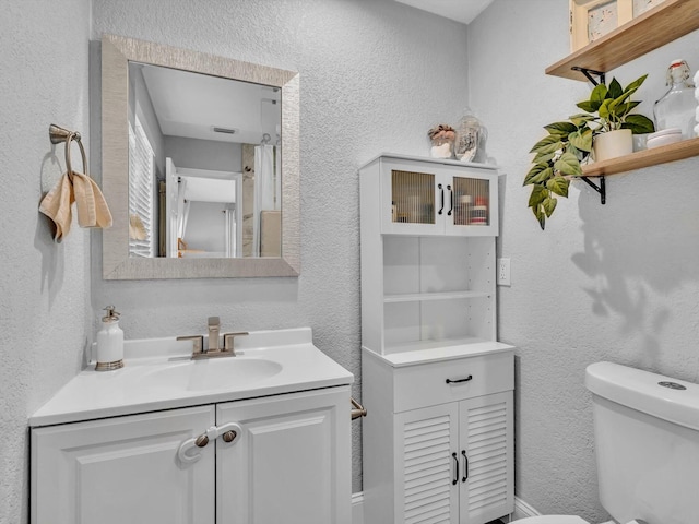 full bath featuring a textured wall, toilet, and vanity