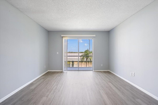 spare room featuring baseboards, a textured ceiling, and wood finished floors