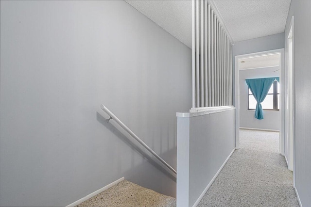 stairs featuring baseboards, a textured ceiling, and carpet