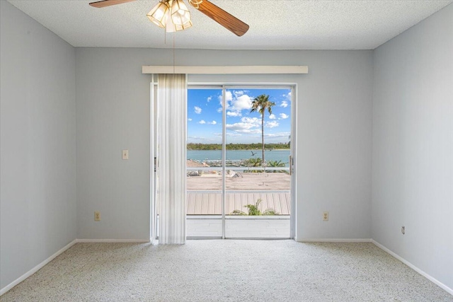 empty room featuring a water view, ceiling fan, baseboards, and carpet