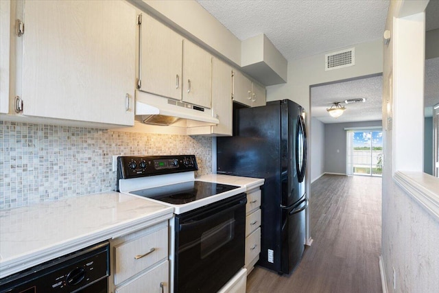 kitchen with a textured ceiling, visible vents, light countertops, black appliances, and under cabinet range hood