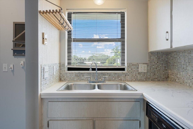 kitchen featuring a sink, dishwasher, tasteful backsplash, and light countertops