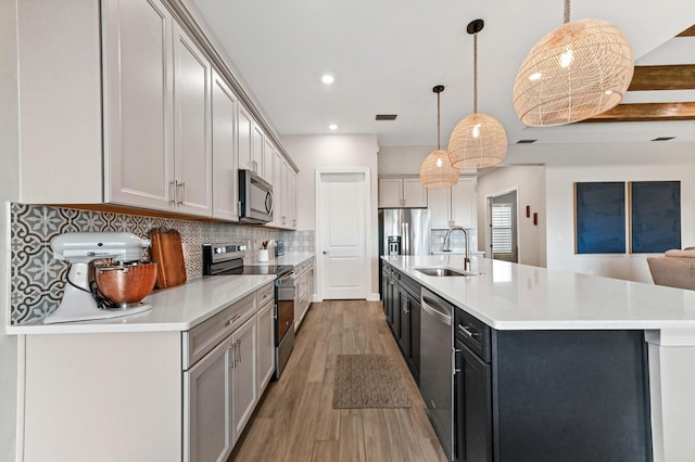 9891 SW Legacy Dr, Stuart, FL 34997 - kitchen with appliances with stainless steel finishes, light countertops, light wood-style floors, tasteful backsplash, and a large island with sink
