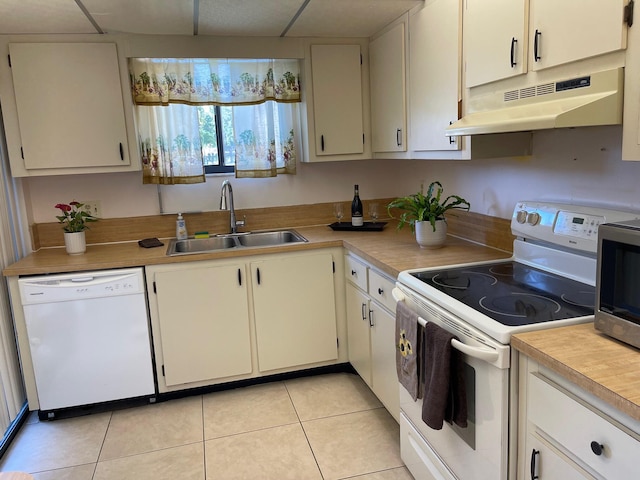 kitchen with white appliances, under cabinet range hood, a sink, and light countertops