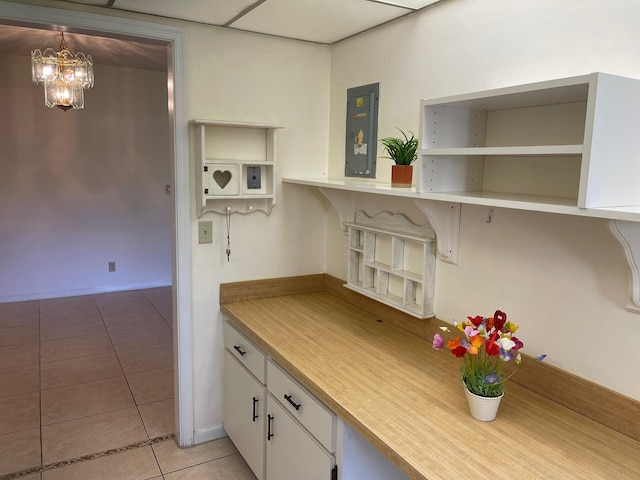 kitchen featuring electric panel, light tile patterned floors, open shelves, a chandelier, and white cabinets