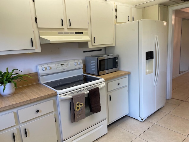 kitchen with white appliances, under cabinet range hood, light tile patterned floors, and light countertops