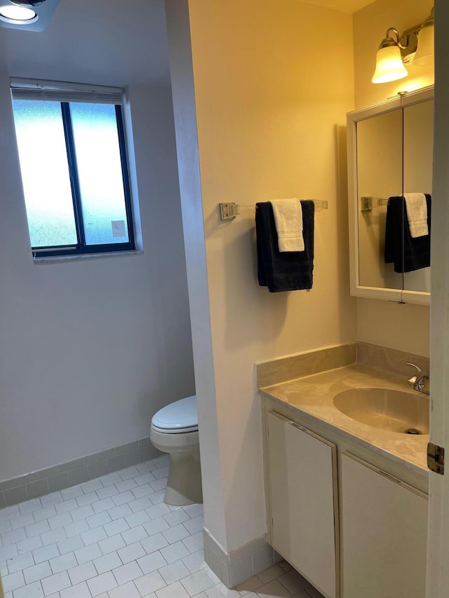 bathroom featuring baseboards, tile patterned flooring, toilet, and vanity