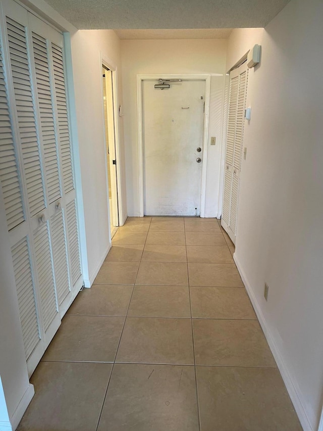 hallway featuring tile patterned flooring and baseboards
