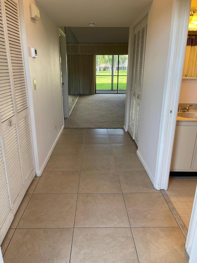 hall featuring light tile patterned floors and baseboards
