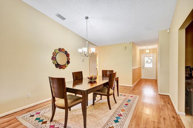 124 Mayfair Ln, Boynton Beach, FL 33426 - dining room with light wood-type flooring, a chandelier, and a textured ceiling