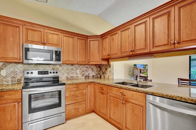 124 Mayfair Ln, Boynton Beach, FL 33426 - kitchen with stainless steel appliances, lofted ceiling, backsplash, brown cabinets, and a textured ceiling