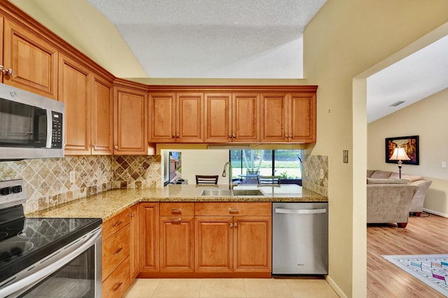 124 Mayfair Ln, Boynton Beach, FL 33426 - kitchen featuring stainless steel appliances, lofted ceiling, tasteful backsplash, brown cabinetry, and light stone countertops