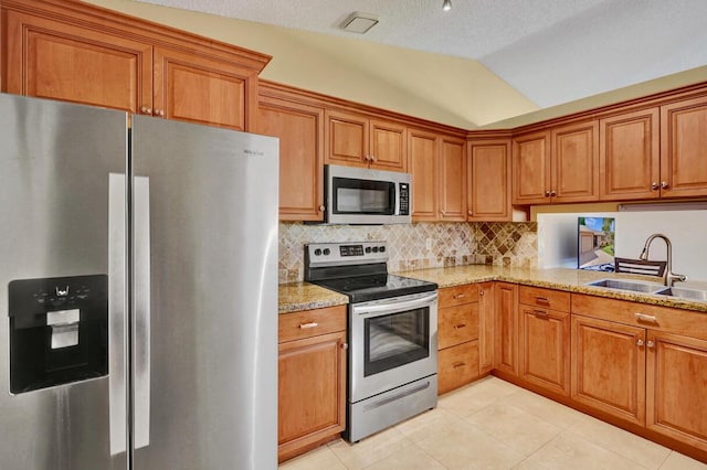 124 Mayfair Ln, Boynton Beach, FL 33426 - kitchen featuring appliances with stainless steel finishes, brown cabinets, light tile patterned floors, backsplash, and vaulted ceiling