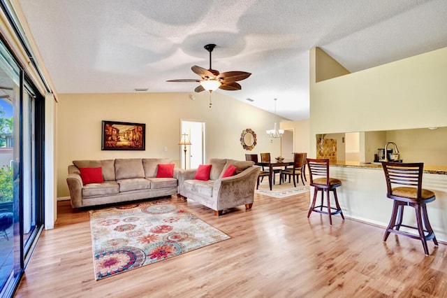 124 Mayfair Ln, Boynton Beach, FL 33426 - living room featuring vaulted ceiling, light wood-style floors, ceiling fan, a chandelier, and a textured ceiling