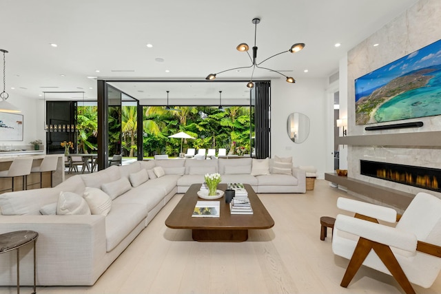 living room with an inviting chandelier, a wall of windows, recessed lighting, and a high end fireplace