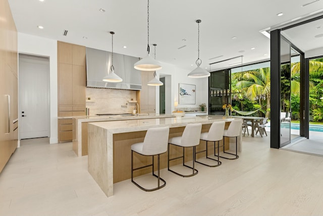 kitchen with decorative backsplash, a spacious island, light stone countertops, a wall of windows, and modern cabinets