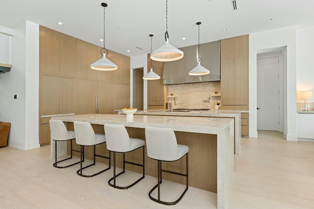 kitchen featuring a breakfast bar, modern cabinets, a large island with sink, and decorative backsplash