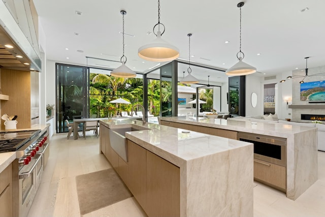 kitchen with range with two ovens, a large island with sink, modern cabinets, and a sink