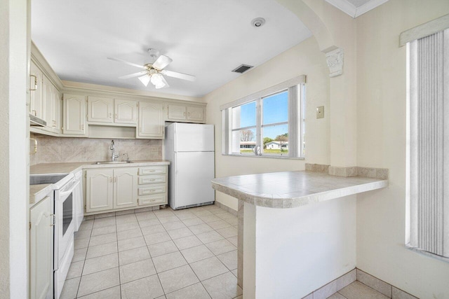 kitchen with ceiling fan, white appliances, a peninsula, visible vents, and a sink