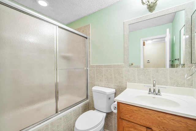 bathroom featuring vanity, tile walls, a textured ceiling, and toilet