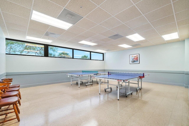 recreation room with tile patterned floors, a paneled ceiling, and baseboards