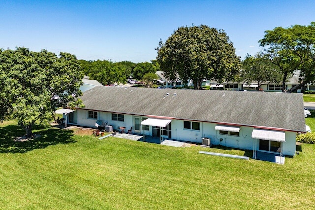 rear view of house featuring a yard, central air condition unit, a shingled roof, and a patio area