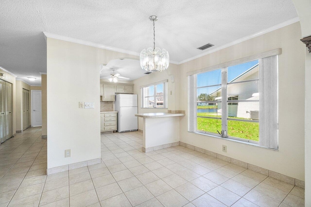 kitchen featuring a peninsula, freestanding refrigerator, ornamental molding, and visible vents