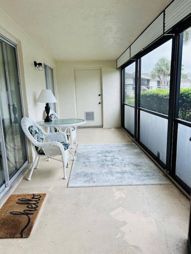 sunroom / solarium with visible vents, unfinished concrete flooring, and a textured ceiling