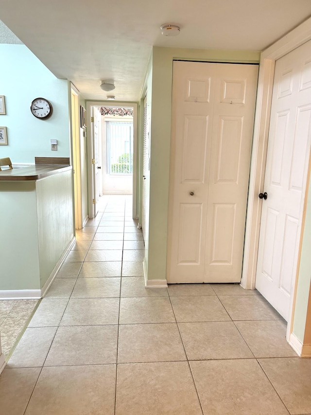hallway featuring light tile patterned floors and baseboards