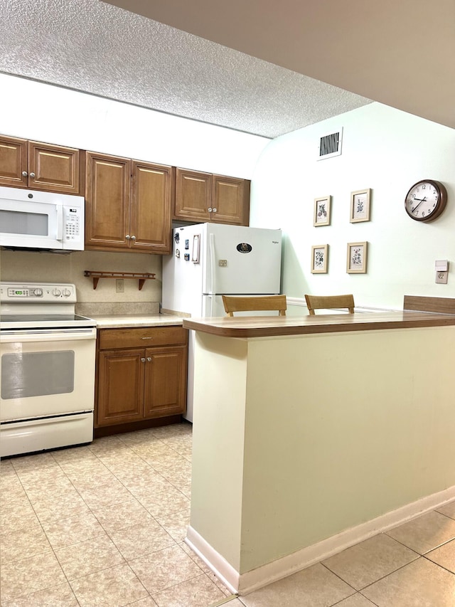 kitchen featuring light tile patterned floors, white appliances, a textured ceiling, visible vents, and light countertops