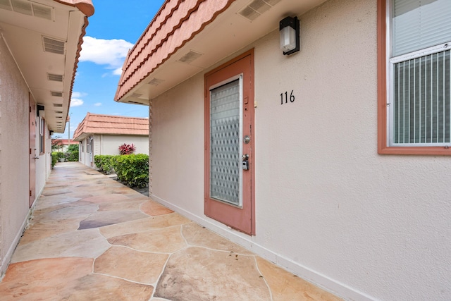 116 Seville D, Delray Beach, FL 33446 - entrance to property featuring a patio area, stucco siding, and visible vents