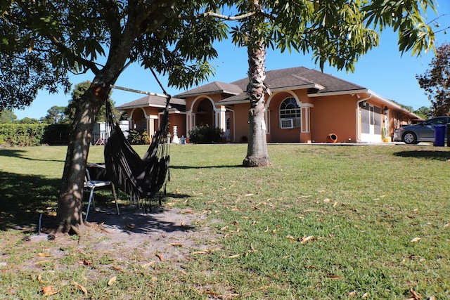 view of front facade featuring a front yard, cooling unit, and stucco siding