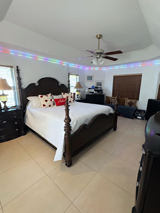 bedroom featuring light tile patterned floors, a tray ceiling, and ceiling fan