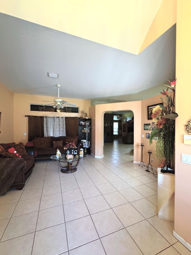 living area featuring a ceiling fan, light tile patterned flooring, visible vents, lofted ceiling, and arched walkways