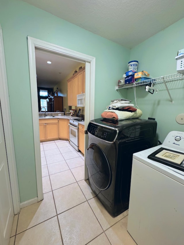 laundry room featuring light tile patterned flooring, laundry area, washing machine and clothes dryer, and a sink