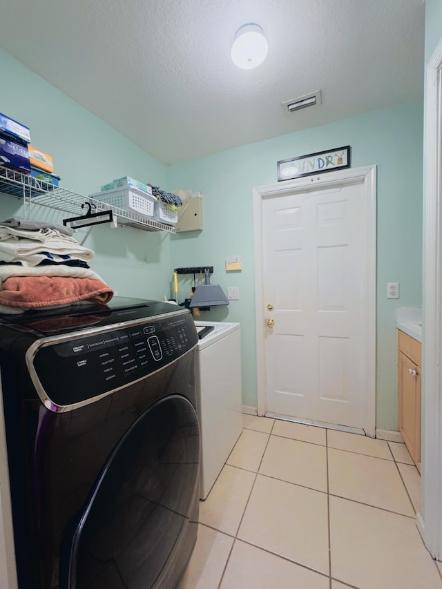 laundry area with visible vents, light tile patterned floors, laundry area, a textured ceiling, and washer and clothes dryer