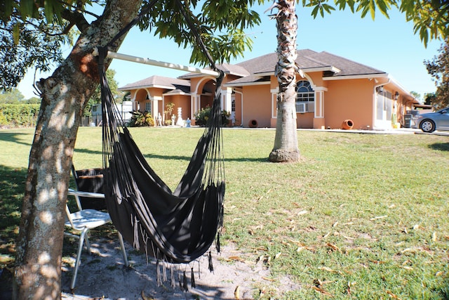 ranch-style house with stucco siding, fence, and a front lawn