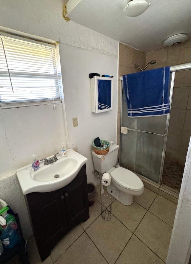 bathroom featuring toilet, a stall shower, vanity, and tile patterned flooring