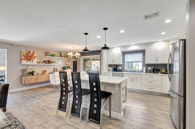 6122 Overland Pl, Delray Beach, FL 33484 - kitchen with white cabinets, visible vents, a sink, freestanding refrigerator, and a notable chandelier