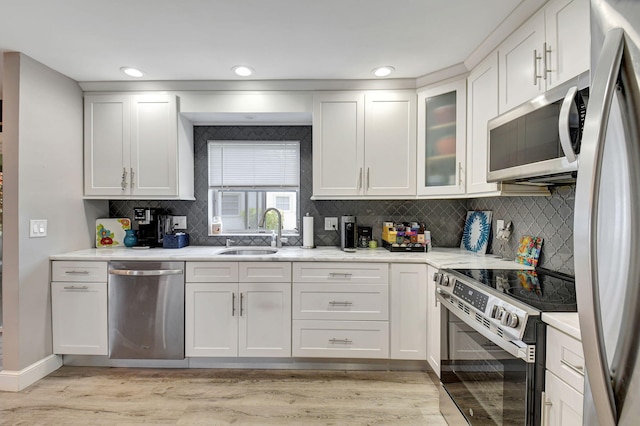 6122 Overland Pl, Delray Beach, FL 33484 - kitchen with tasteful backsplash, white cabinets, a sink, light wood-type flooring, and stainless steel appliances